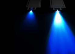 Vor schwarzem Hintergrund gehen von zwei Lampen im oberen Bilddrittel ein schwacher Lichtkegel (links) und ein sehr heller (rechts) aus. Das Licht verläuft vom Weißen nach unten ins Bläuliche.